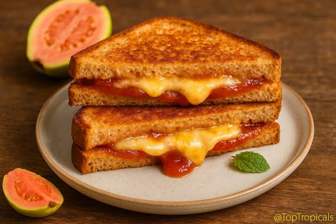 Two toasted bread slices with melty cheese and tomato jam filling on a plate, with fig halves in the background and a small mint leaf garnish.